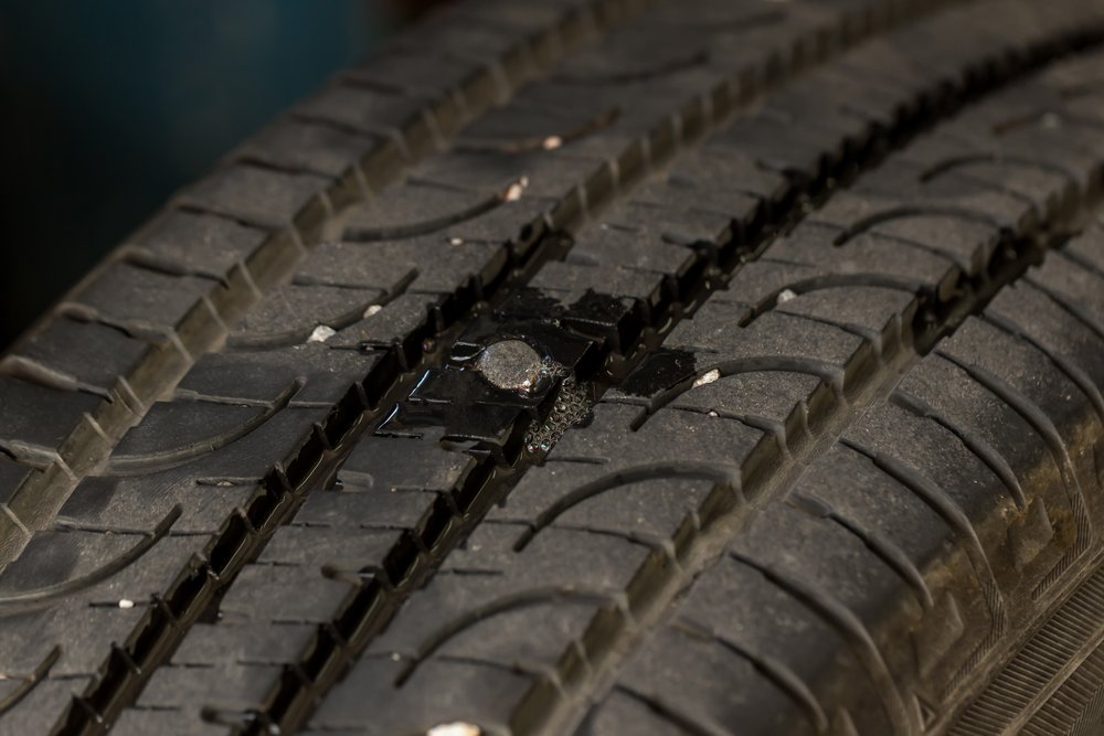 Close up shot of car tyre tread with nail embedded 