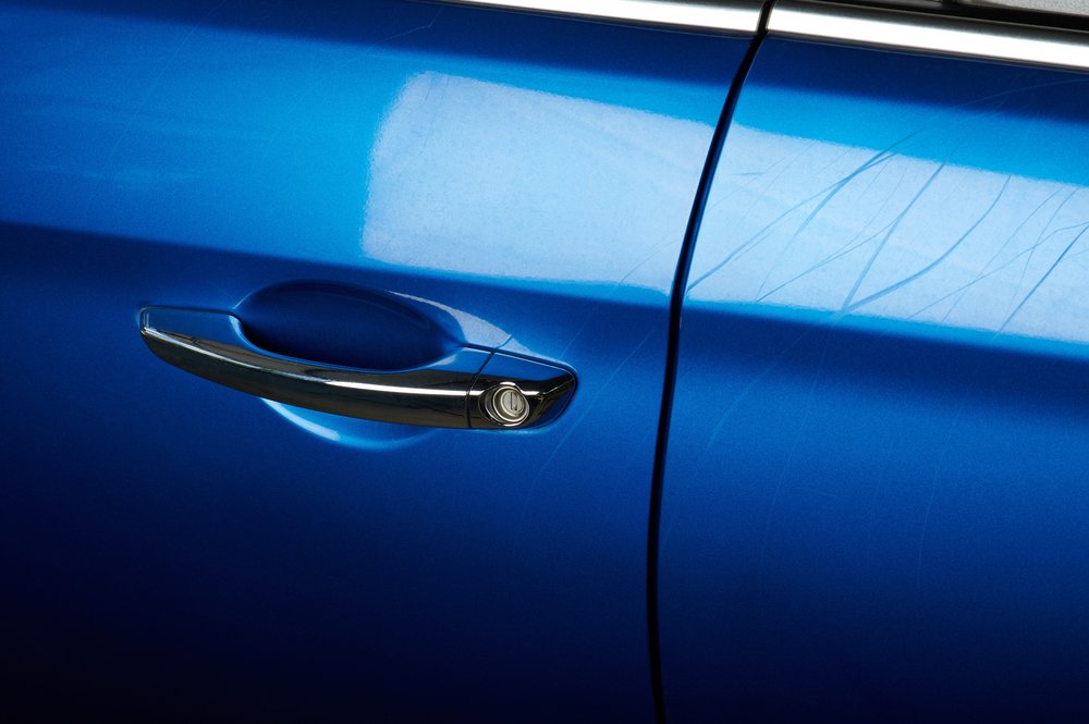 Close up of a blue car door with scratches
